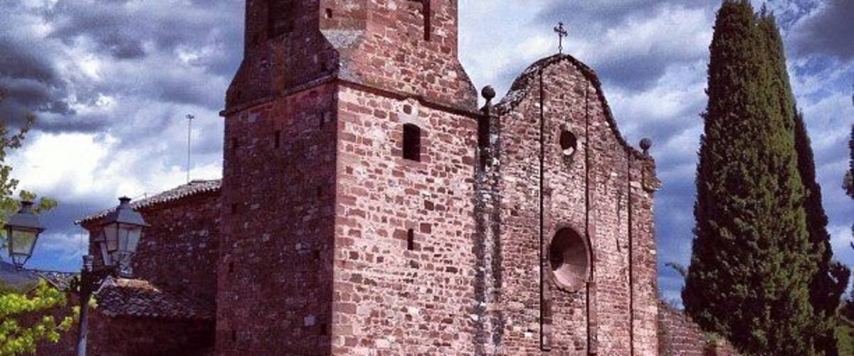 A historic stone church with a bell tower and arched windows.