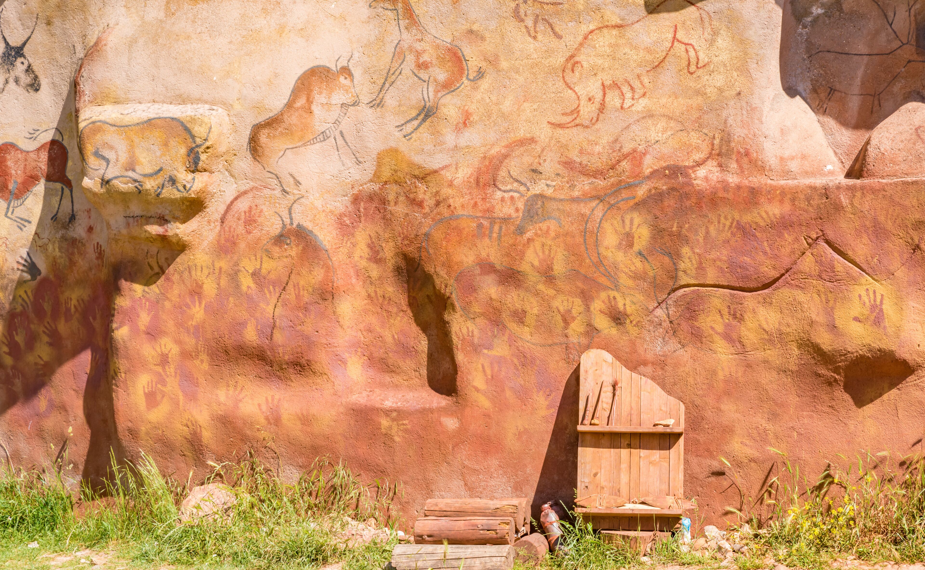 A cave wall with ancient petroglyphs and a wooden structure.