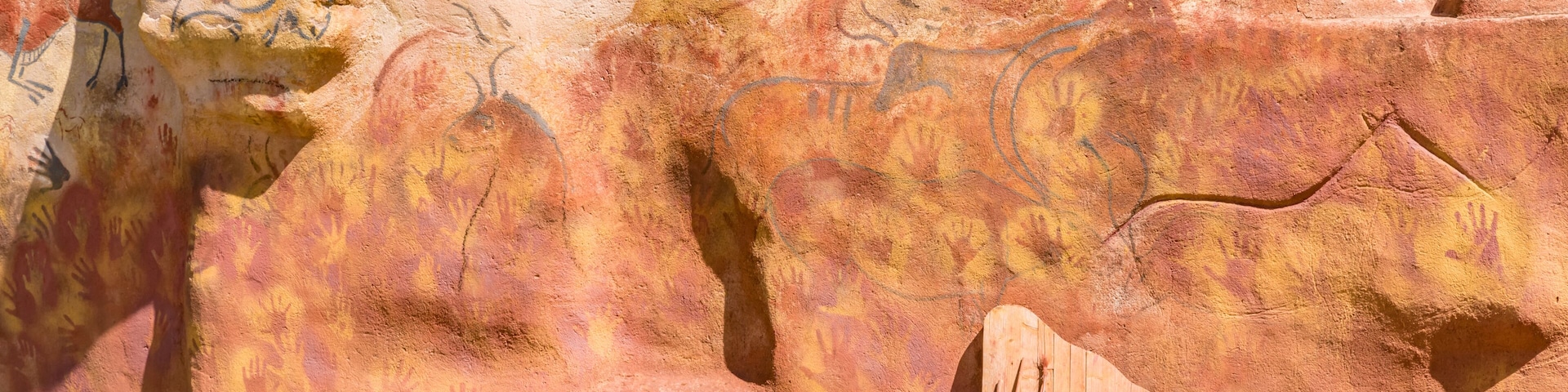 A cave wall with ancient petroglyphs and a wooden structure.