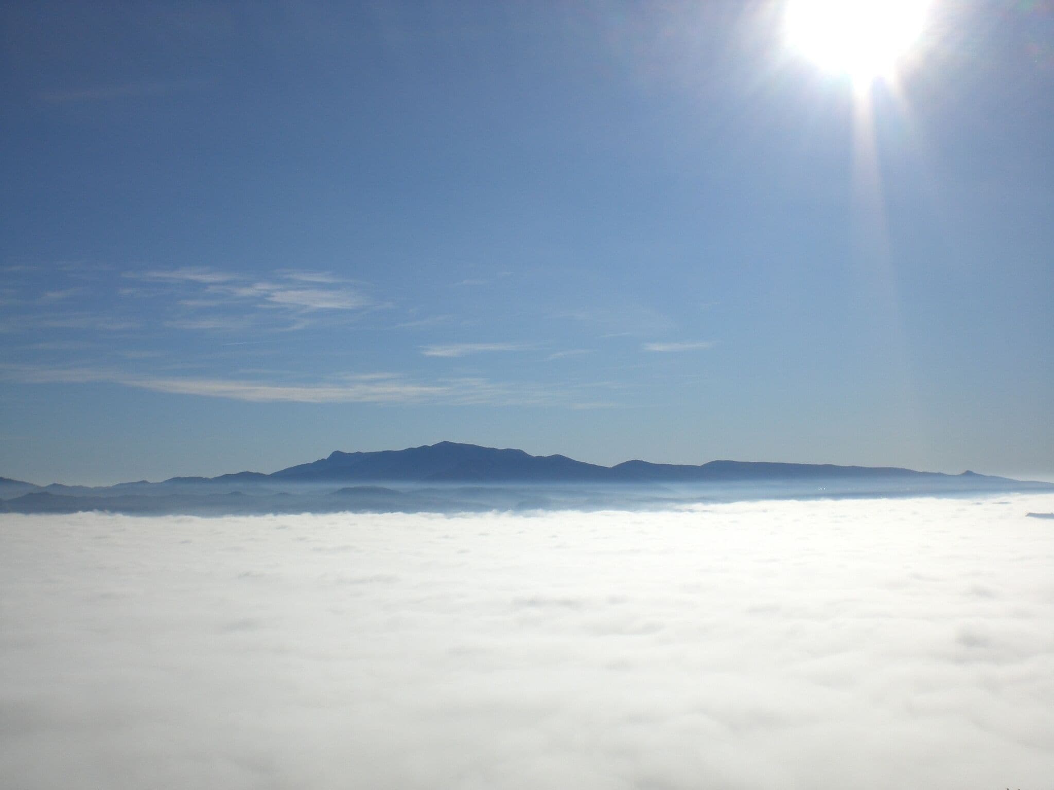 A mountain range above a sea of clouds with a clear sky.