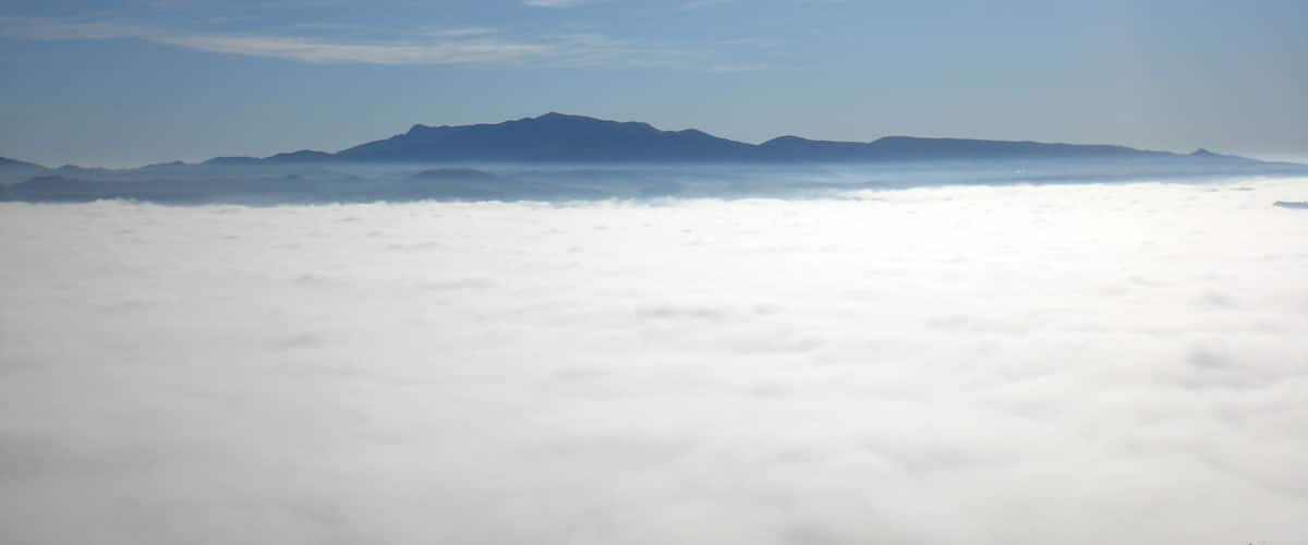 A mountain range above a sea of clouds with a clear sky.