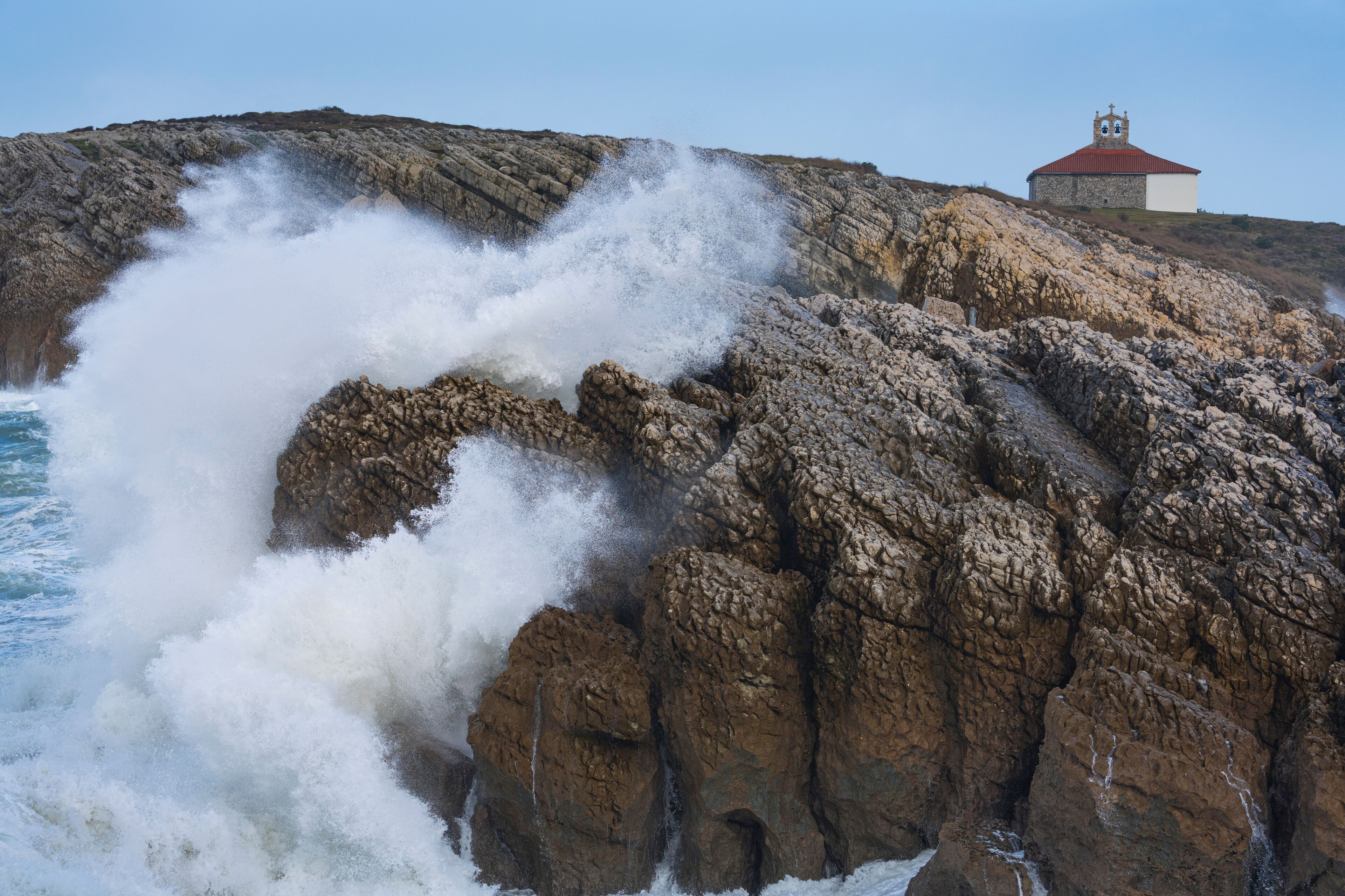 A rocky coastline with a church on a hill.