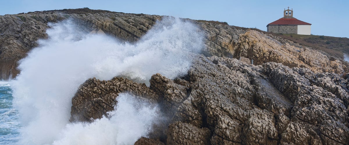 A rocky coastline with a church on a hill.
