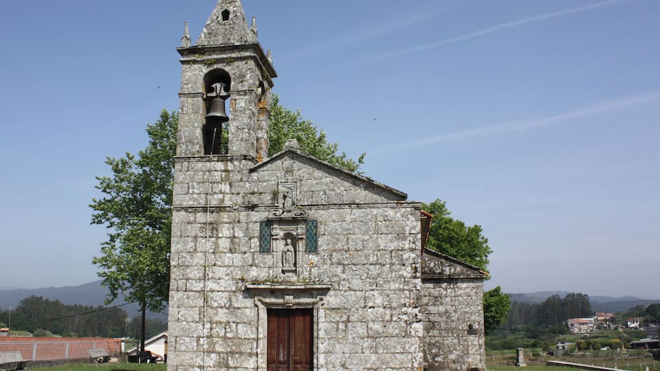 A small stone church with a bell tower and a wooden door.