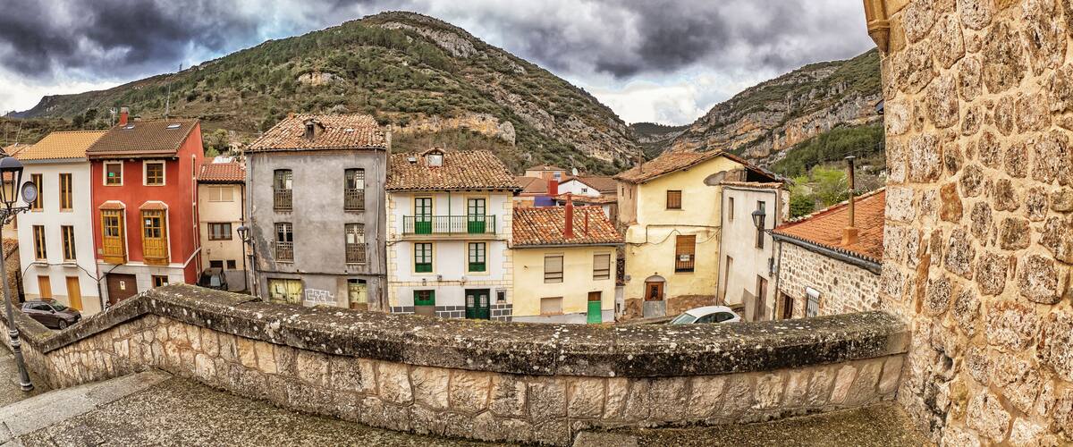A stone wall, a stone bridge, and buildings with red and yellow roofs.