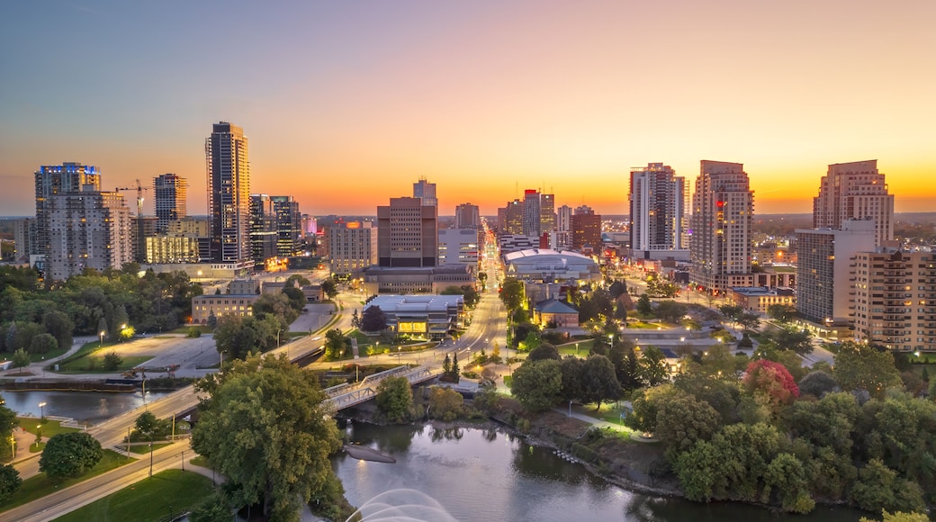 A cityscape with high-rise buildings, a river, and a bridge during sunset.