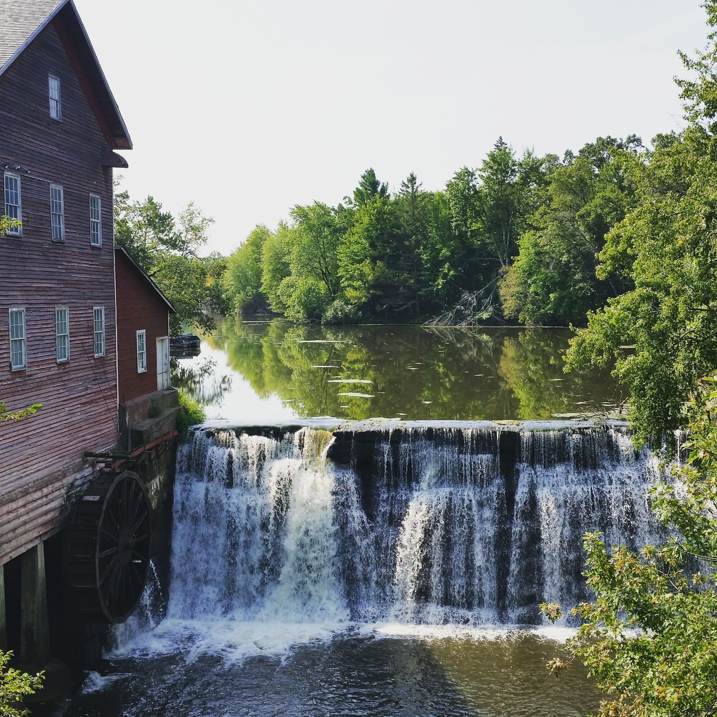 A wooden mill with a water wheel and a waterfall.
