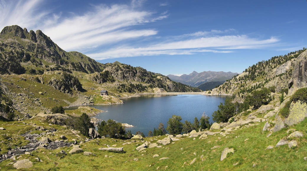 A mountainous landscape with a lake, rocky terrain, and a small cabin.