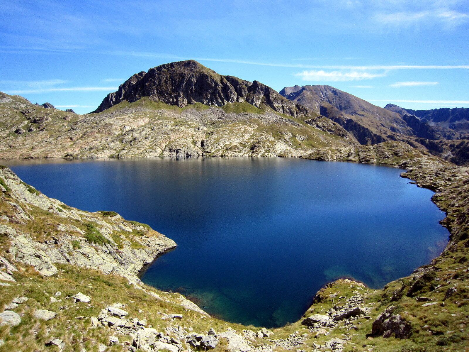 A mountain lake surrounded by rocky terrain and distant mountains.