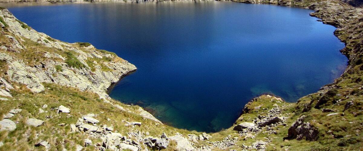 A mountain lake surrounded by rocky terrain and distant mountains.