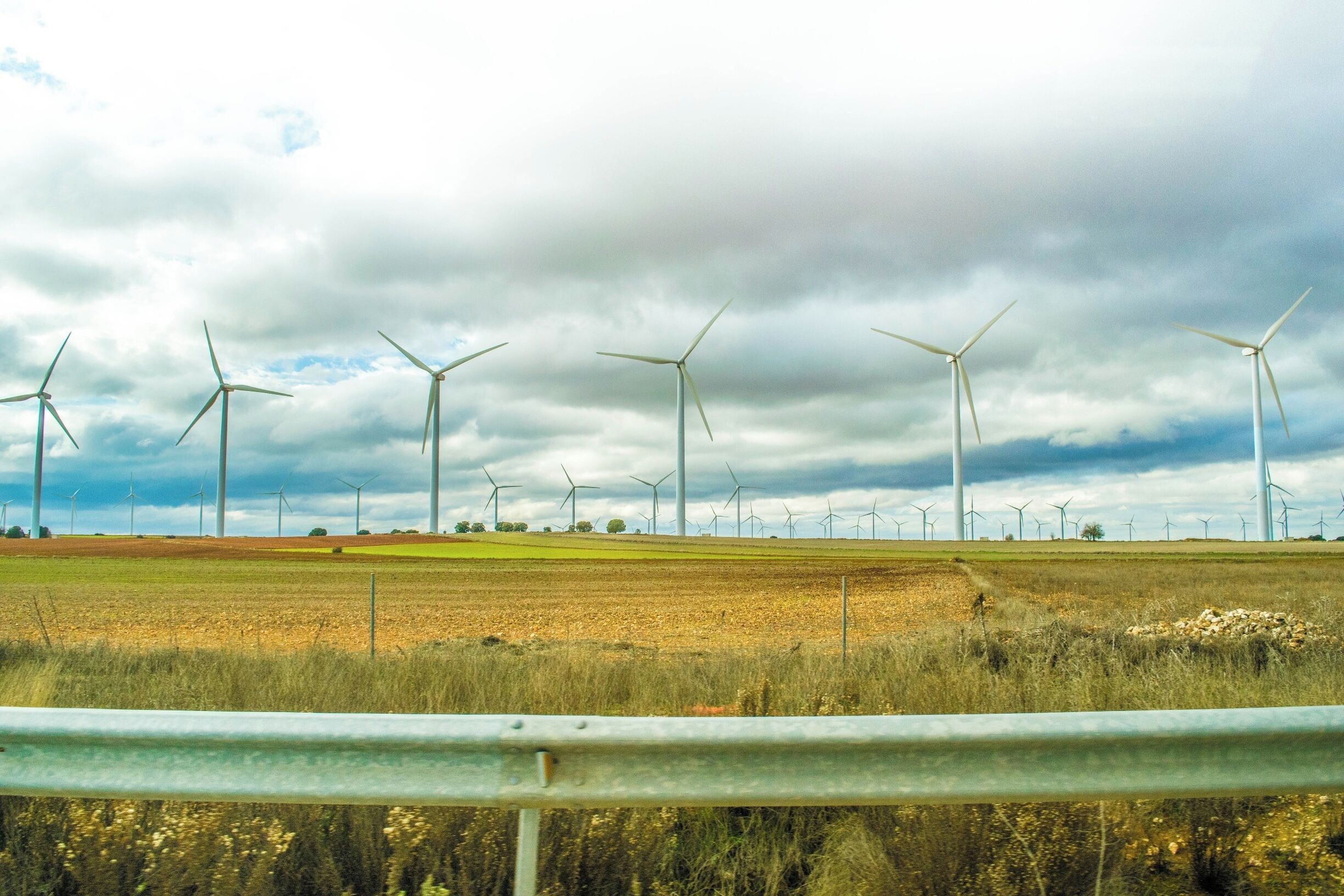 A wind farm with multiple wind turbines in a field under a cloudy sky.