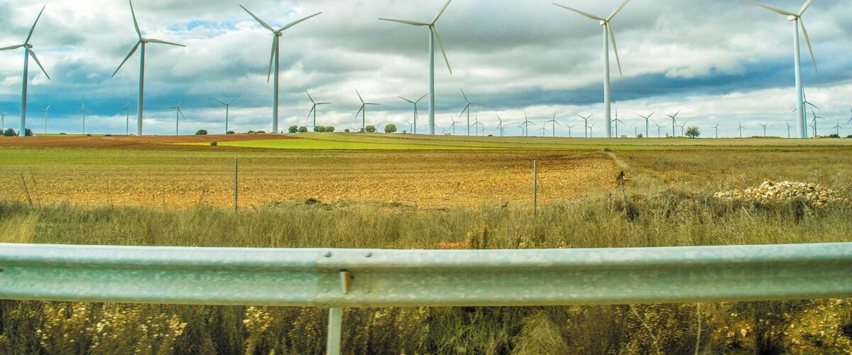 A wind farm with multiple wind turbines in a field under a cloudy sky.