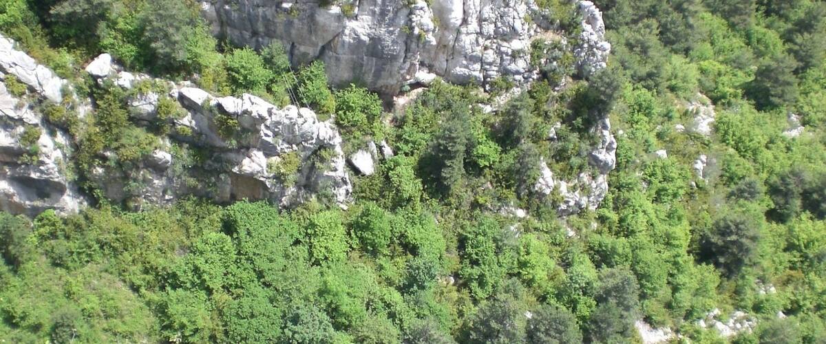 A rocky mountain with dense green vegetation and a winding road.