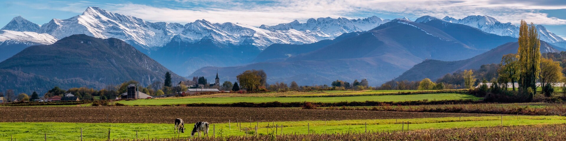 Panorama of a farm and field at the base of the Pyrenees Mountains