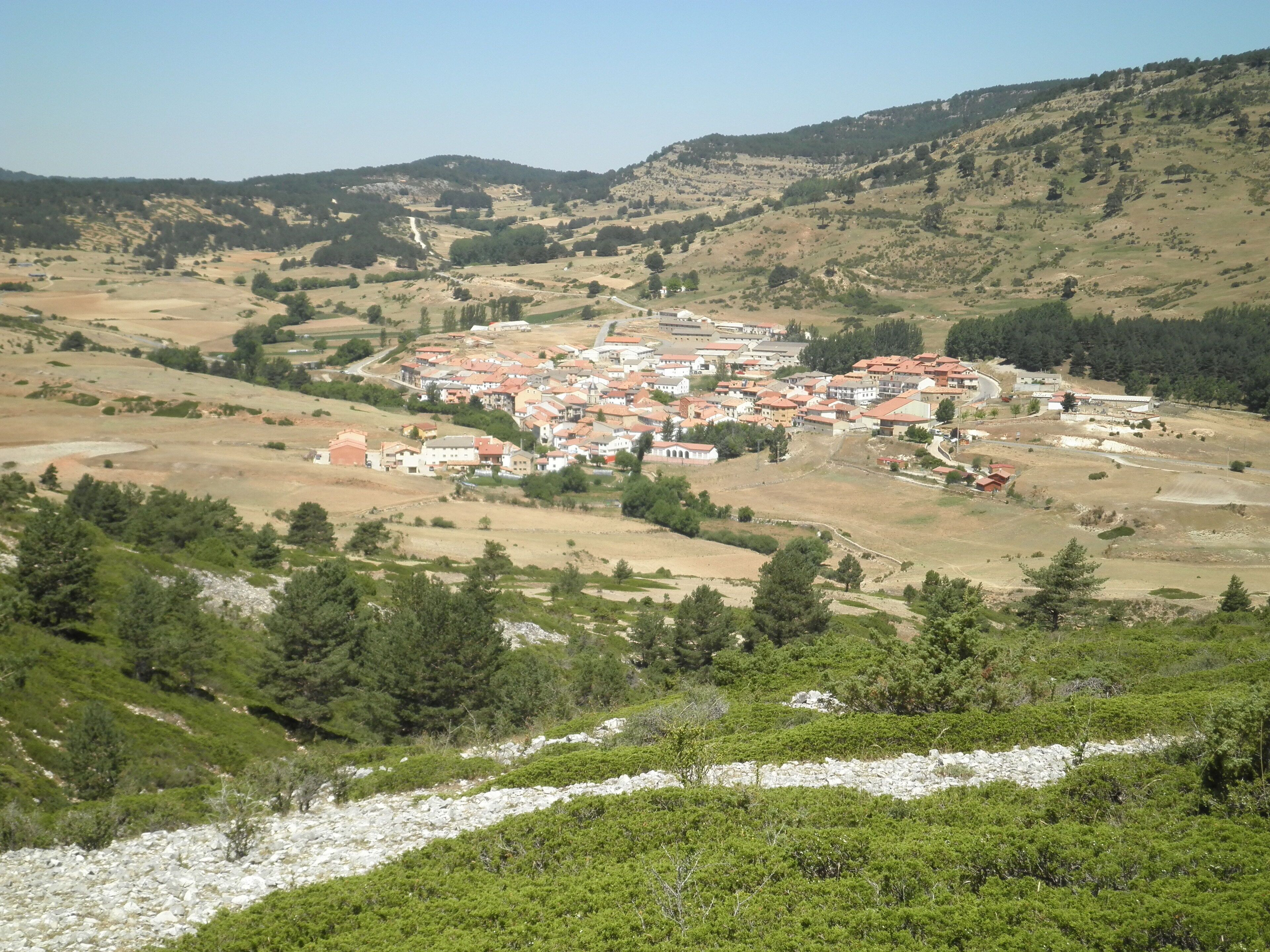 A hillside village with terraced houses and a river in the foreground.