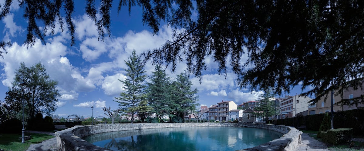 A stone fountain surrounded by trees and buildings.
