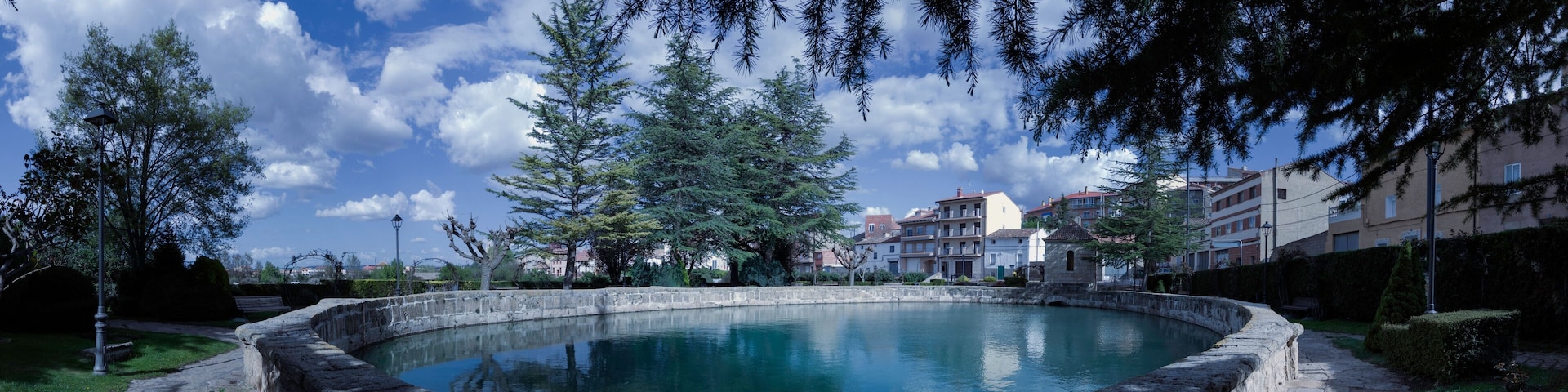 A stone fountain surrounded by trees and buildings.