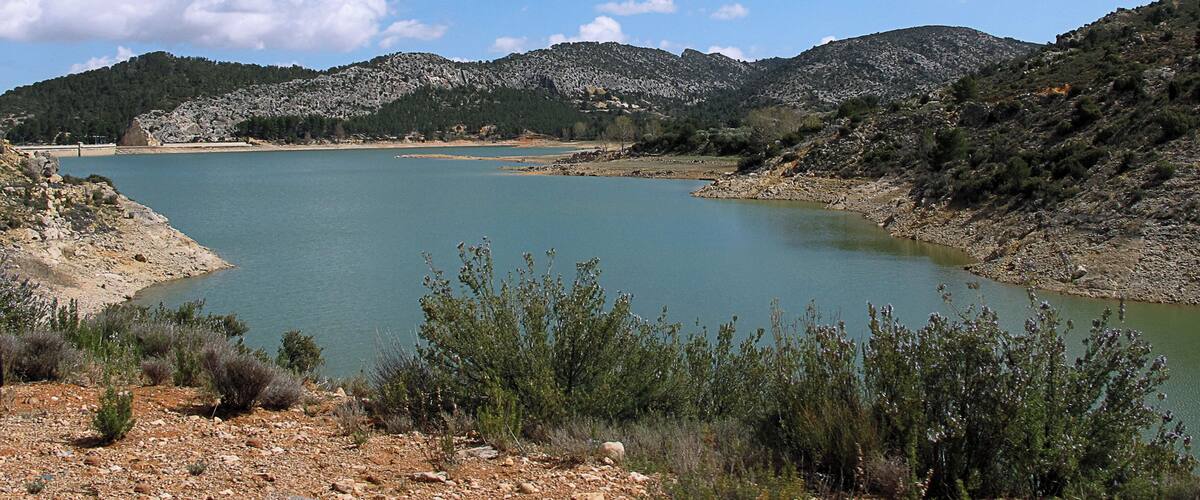 A lake surrounded by rocky hills and sparse vegetation.