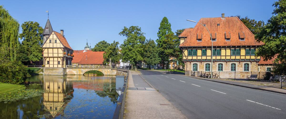 A canal with a bridge, traditional half-timbered houses, and a clear blue sky.