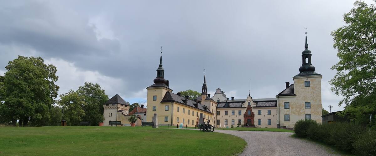 A historic building with two prominent towers and a gravel path leading to it.