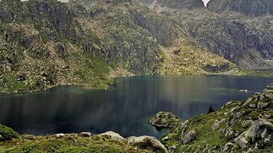 Um lago de montanha rodeado por terreno rochoso e acidentado.