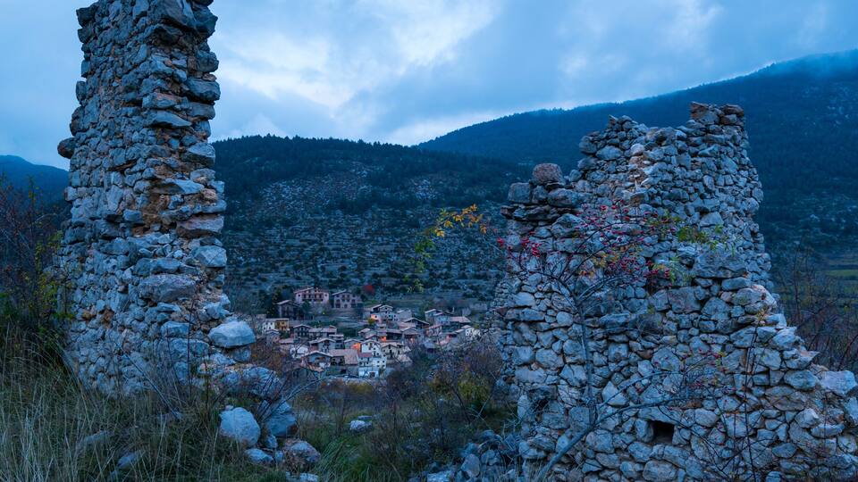A mountainous landscape with stone ruins and a village in the valley.