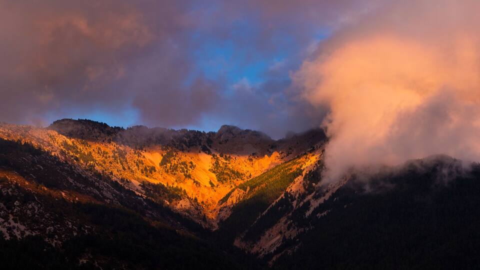 A mountain range with snow-capped peaks and a valley.