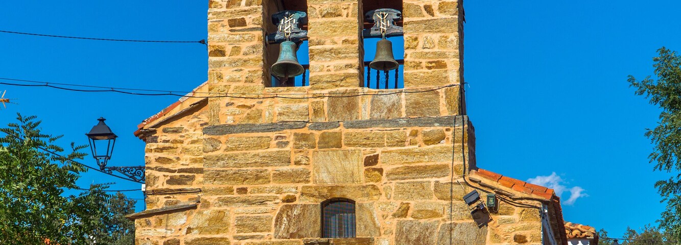 Una iglesia de piedra con una puerta azul y dos campanarios.