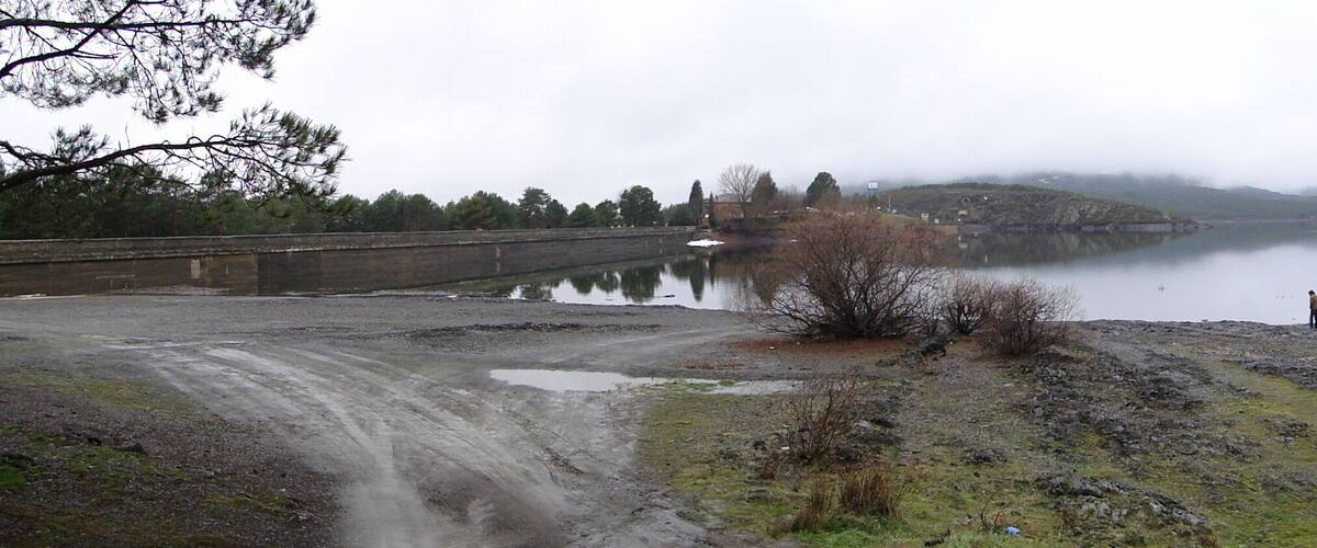 A lake surrounded by hills and a bridge.