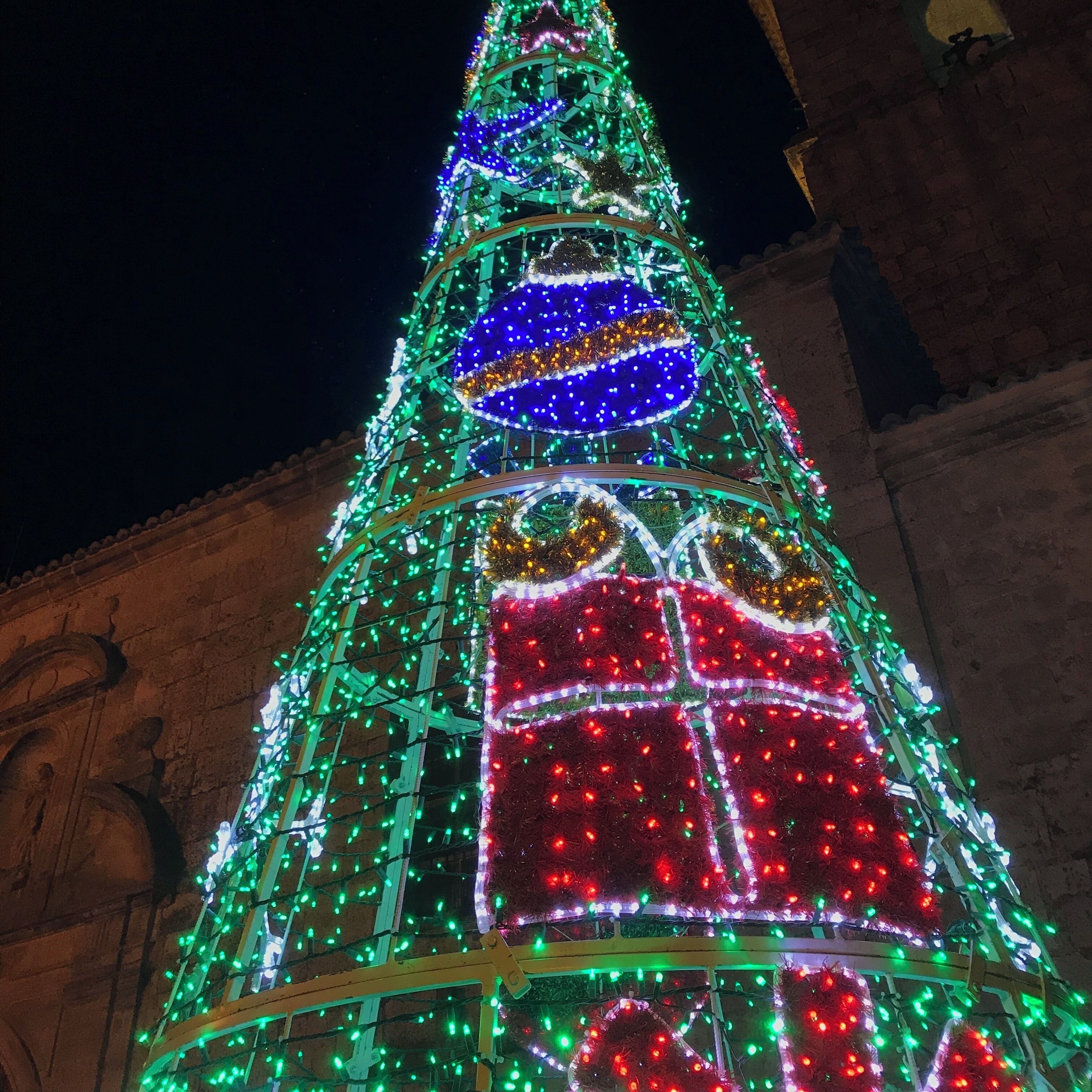 A brightly lit Christmas tree with green, red, and blue decorations.