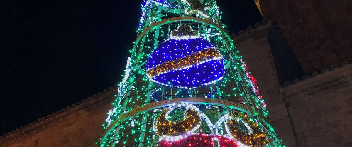 A brightly lit Christmas tree with green, red, and blue decorations.