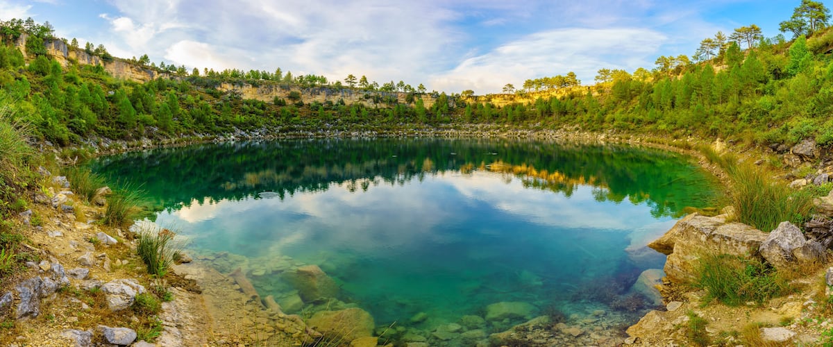 Un lac aux eaux limpides, entouré d’un paysage rocheux et de forêts.