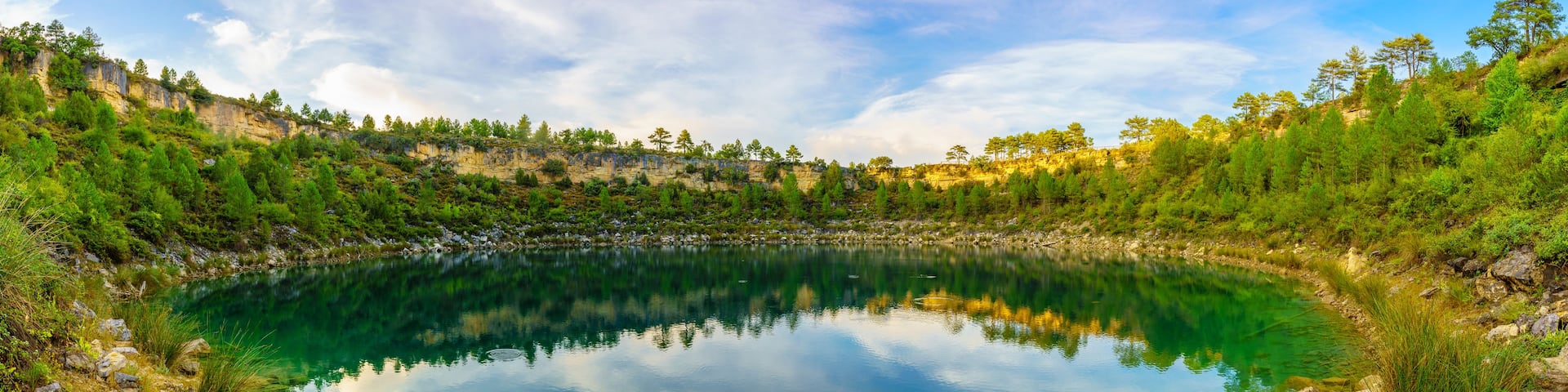 A clear lake surrounded by rocky terrain and trees.