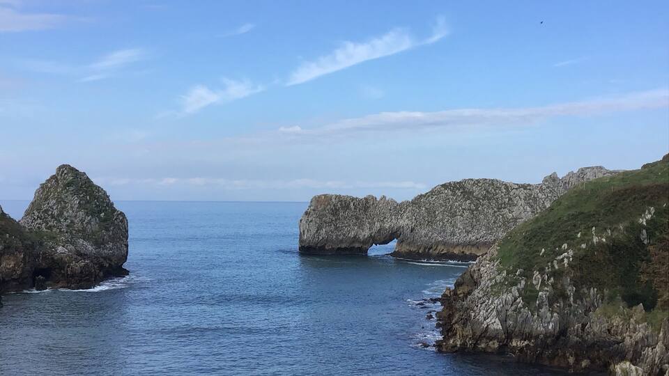 A coastal landscape with rocky formations and a clear blue sky.