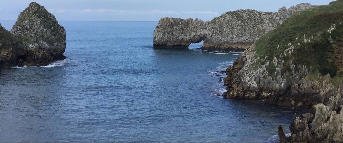 A coastal landscape with rocky formations and a clear blue sky.