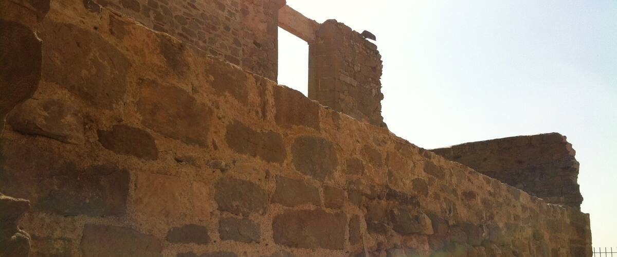 An ancient stone wall with a partially intact archway.
