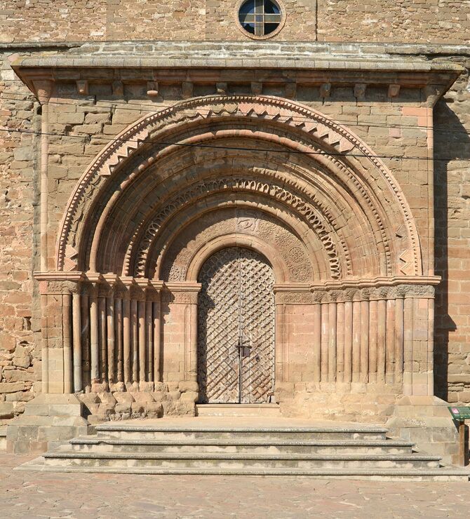 An arched doorway with intricate stone carvings and a barred door.