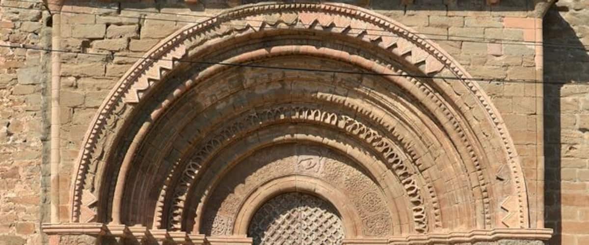 An arched doorway with intricate stone carvings and a barred door.