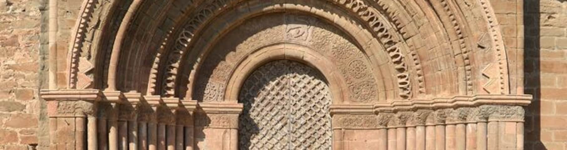 An arched doorway with intricate stone carvings and a barred door.