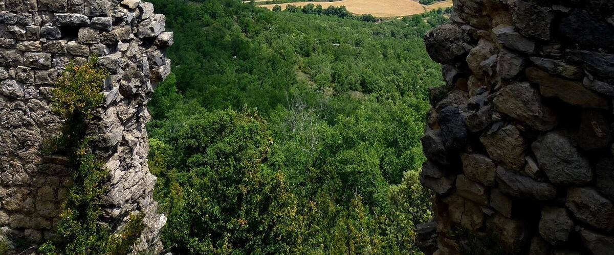 A stone ruin with a view of a valley and mountains.