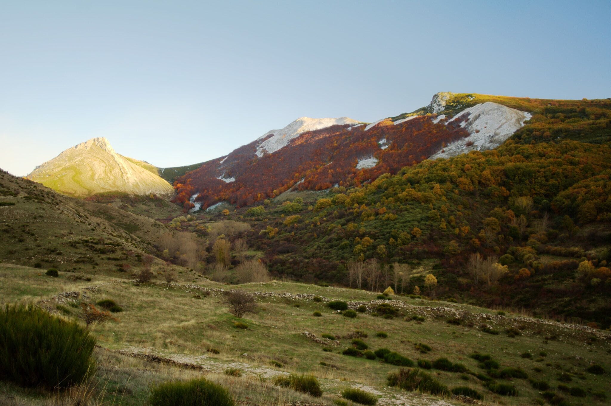 A mountainous landscape with autumn foliage, a prominent peak, and a valley.