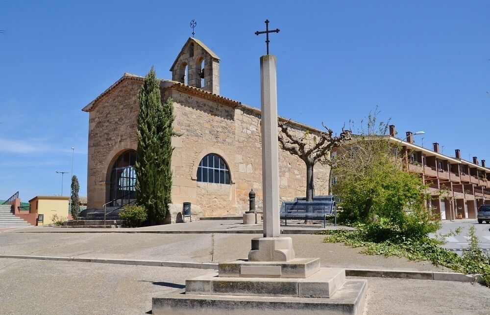 A historic church with a bell tower and a tall cross in front.