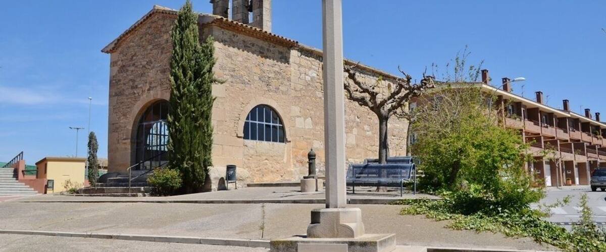 A historic church with a bell tower and a tall cross in front.