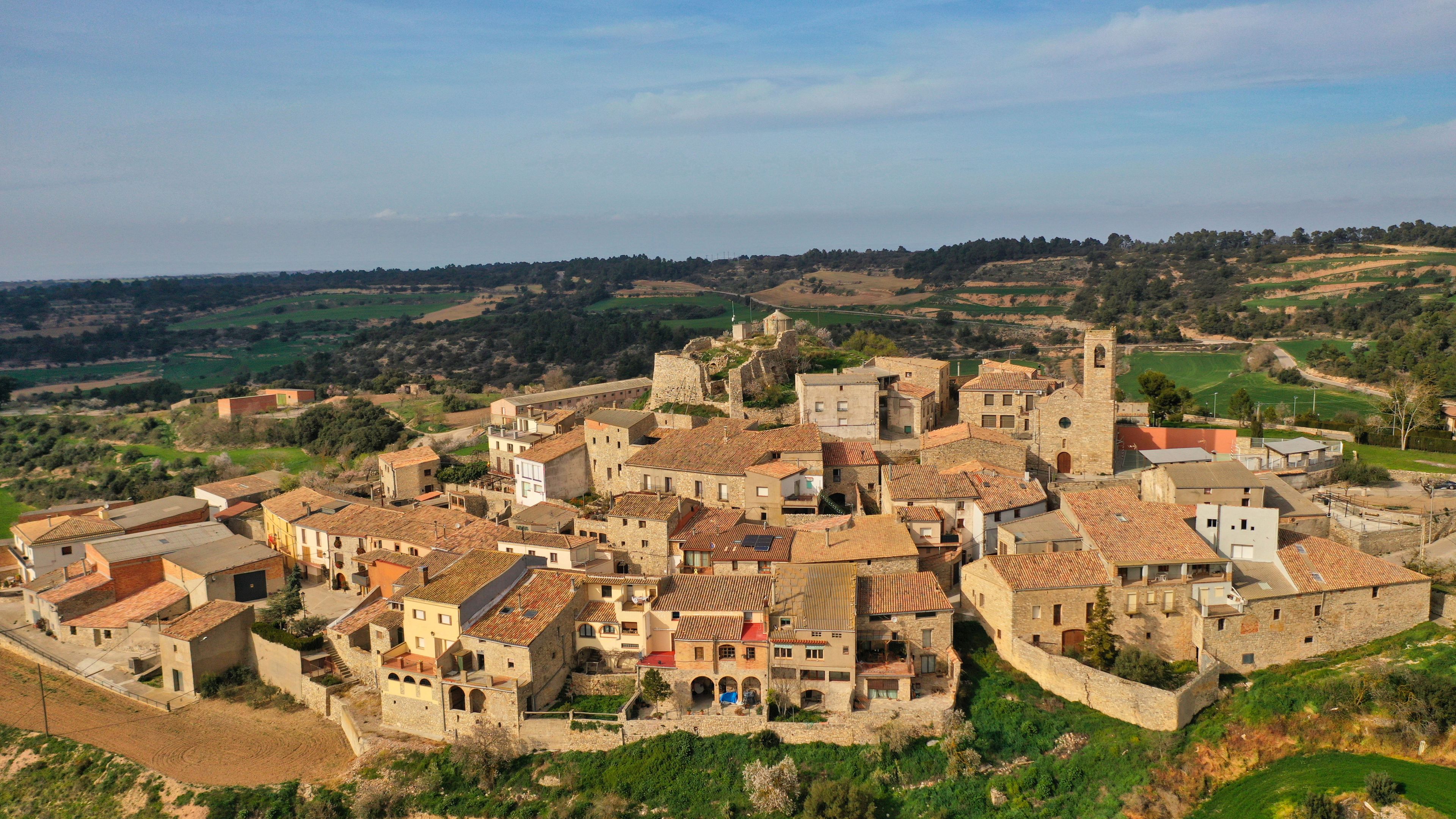 A historic town with stone buildings, a prominent church, and a castle on a hill.