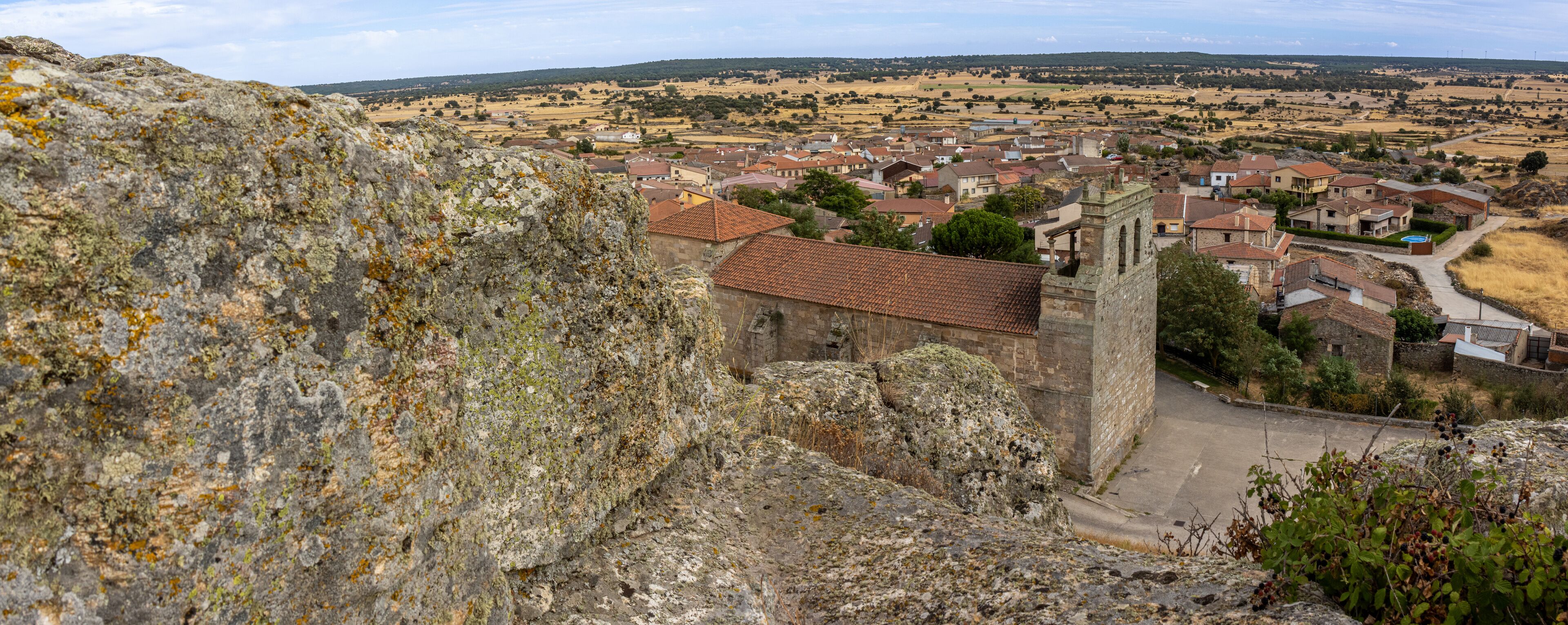 A stone tower, a village with red-tiled roofs, and a rocky foreground.