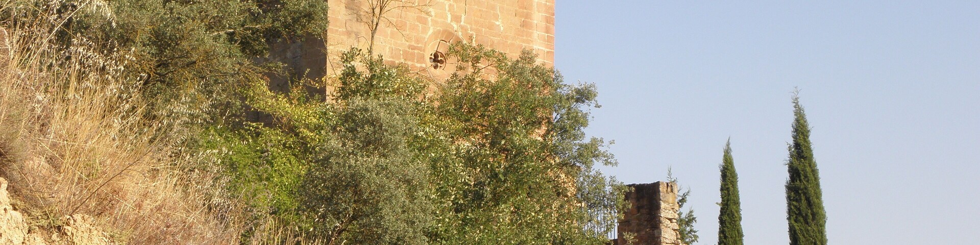 La façana principal i la tàpia del cementiri de l'església vella de Sant Jaume, al poble de Sallent (municipi de Sallent de Solsonès) vista des del camí de Sant Climenç a Sanaüja. Darrere l'església, el cementiri.