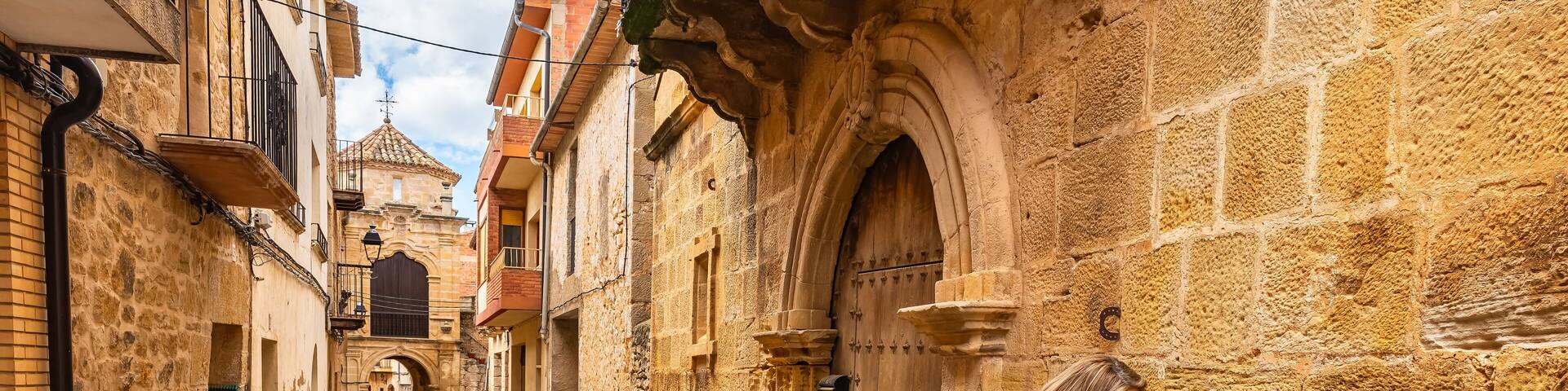 Tourist woman touching the medieval stone of the historic buildings of the town of Cretas, Teruel, Aragon.
