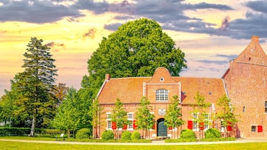 A brick building with a tower, surrounded by trees and a grassy field.