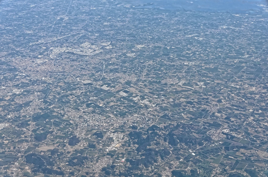 Vista aérea de una zona urbana densamente poblada con edificios residenciales y comerciales, carreteras y áreas verdes.