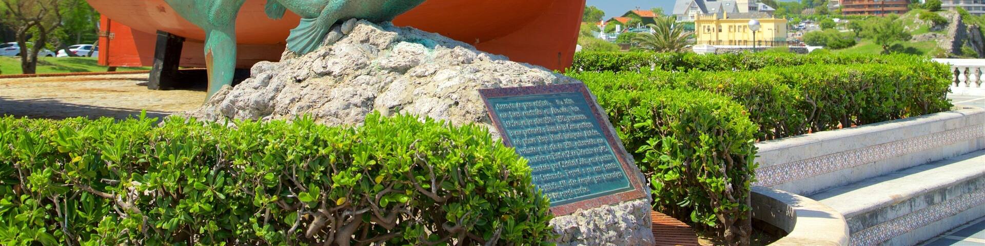 A bronze statue of a mermaid with a ship in the background.